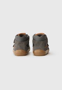 Scarpe high-top grigie in suede con accenti in rete, dotate di chiusura con cinturino in pelle marrone e suola in gomma beige, viste dal retro.