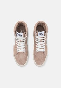 Høye sneakers i lys beige semsket skinn med hvite snøringer, rund tå og polstret krage. Svart logo vist på tungen.