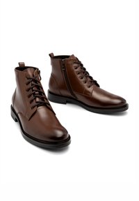 Brązowe skórzane botki do kostki z gładkim wykończeniem, sznurowanym przodem i bocznym zamkiem, na płaskiej podeszwie, z ozdobnym przeszyciem.