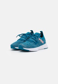 Zapatillas deportivas en color teal, fabricadas con material de punto transpirable, con suela blanca, punta redondeada y un prominente logo rosa en el lateral.