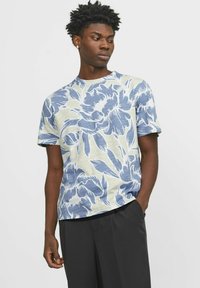 Kortärmad T-shirt med ett stort blommönster i blått på en ljusgrön bakgrund. Tillverkad av mjukt material med en avslappnad passform.