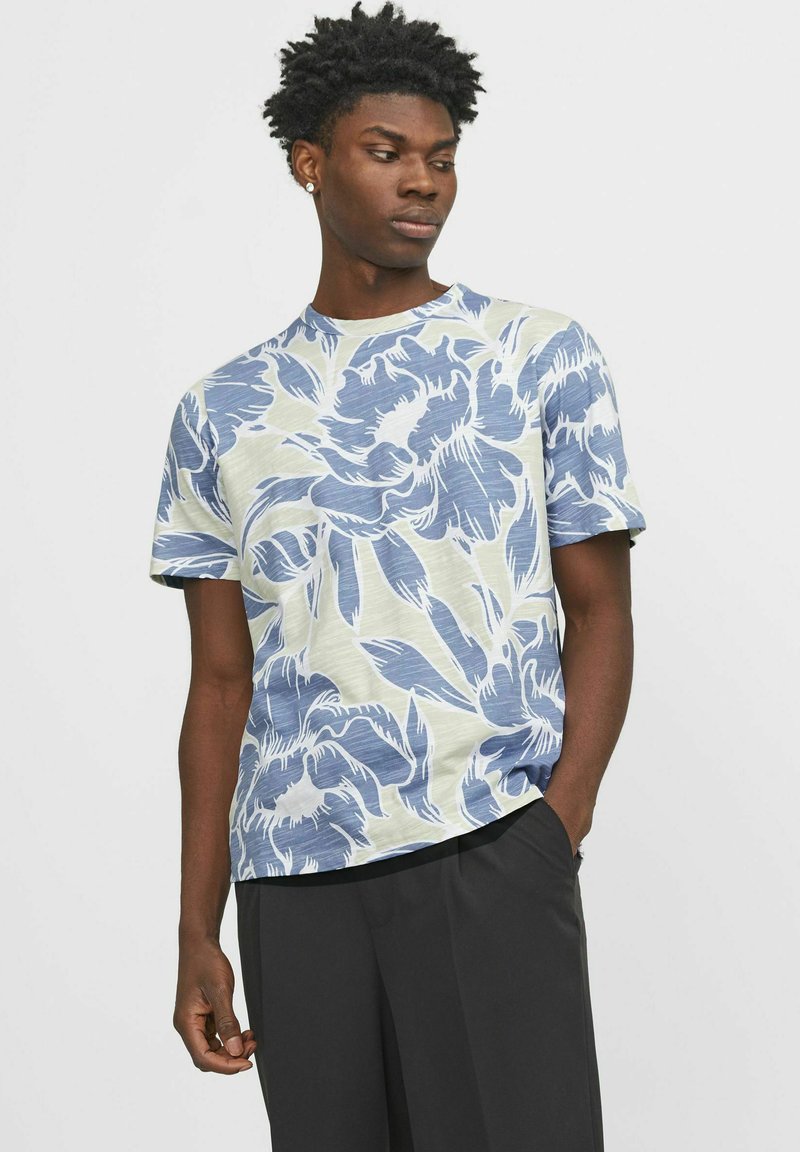 Kortärmad T-shirt med ett stort blommönster i blått på en ljusgrön bakgrund. Tillverkad av mjukt material med en avslappnad passform.