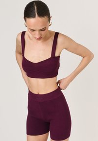 Burgundowy prążkowany crop top z szerokimi ramiączkami i okrągłym dekoltem, zestawiony z szortami z wysokim stanem o prążkowanym wzorze z logo.