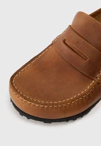 Bruna läderloafers med en slät yta, med en stickad design, ett band över ovandelen och en texturerad svart gummisula.