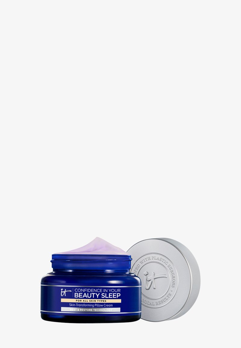 Blaues Glas mit „Vertrauen in deinen Schönheitsschlaf“ hauttransformierender Kissencreme mit silbernem Deckel daneben, der die hellviolette Creme zeigt.