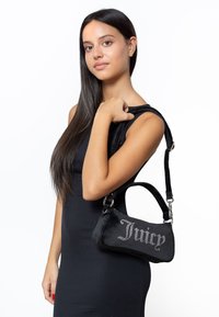 Μαύρη βελούδινη τσάντα χειρός με λογότυπο "Juicy" διακοσμημένο με κρύσταλλους, διαθέτοντας κοντό λουράκι και οβάλ σχήμα. Λείο υλικό.
