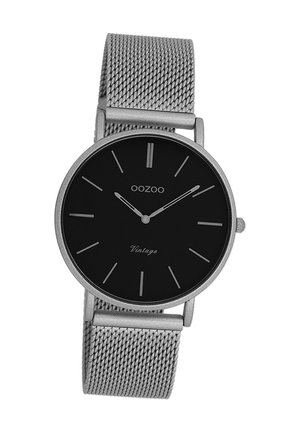 Black dial watch with silver mesh strap, minimalist design, round case, silver hour markers, and subtle "Vintage" text on the face.