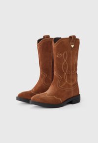Brune semskede cowboy støvler med lynlås, der har gule syninger og et lille guld hjerteaccent nær toppen. Sort gummisål.