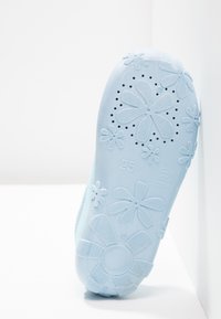 Helles blaues Schuhsohle mit floralen Mustern, strukturiertem Oberflächen und Belüftungslöchern. Größe markiert als 25.