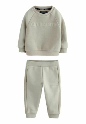 Vaaleanharmaa collegepaita, jossa on teksturoitu kangas ja kohokuvioitu "ALLSAINTS" -logo, yhdistettynä samansävyisiin kapeneviin housuihin, joissa on sivutaskut.