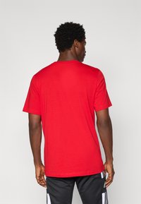 Rød bomulds T-shirt med korte ærmer og rund hals. Stoffet har en glat overflade og let stræk. Minimalistisk design, ingen synlige detaljer.