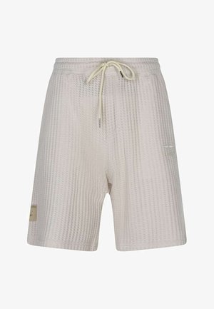 Short en maille texturée beige clair avec taille élastique et cordon crème, avec un petit patch latéral et un détail discret de poche.