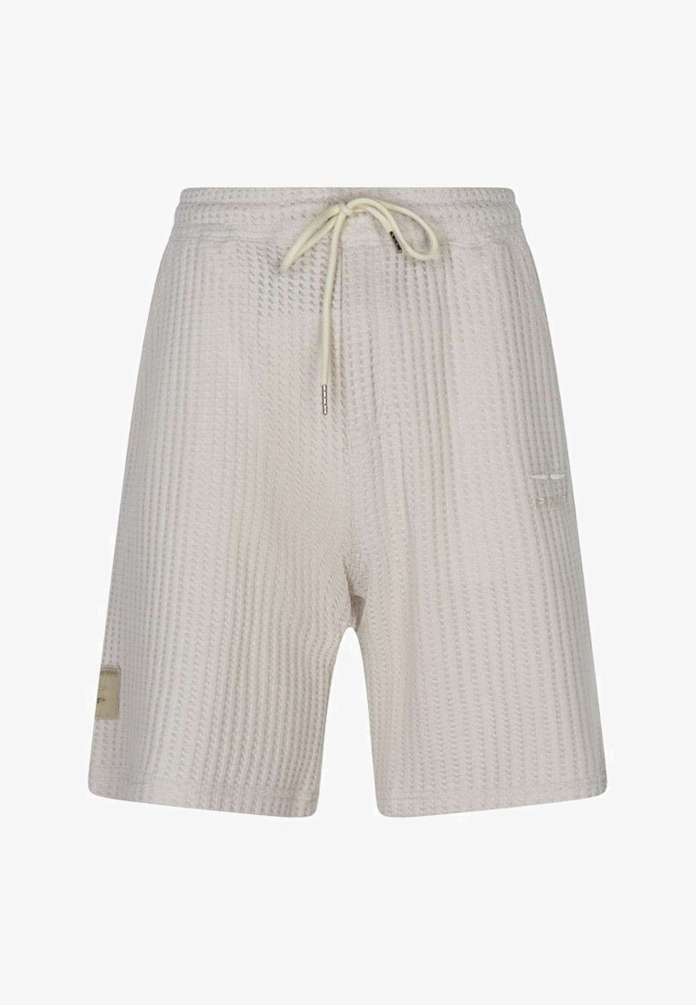 Short en maille texturée beige clair avec taille élastique et cordon crème, avec un petit patch latéral et un détail discret de poche.