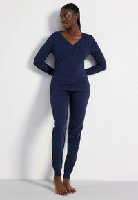 Navy blue pajamas made of soft fabric, featuring long sleeves and fitted legs, with a dotted pattern and a V-neck design.