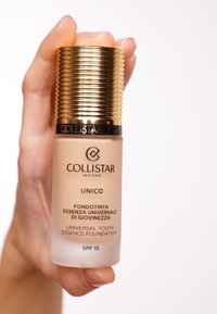 Collistar Unico foundation in a glass bottle with a gold ribbed cap. Features beige liquid inside and SPF 15 label at the bottom.