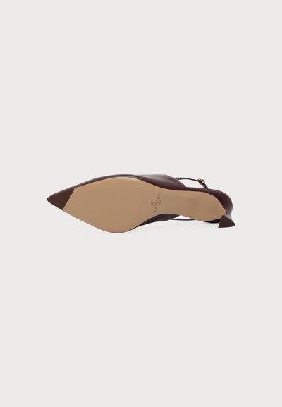 Μπορντό γόβα slingback με μυτερή μύτη, εμφανίζεται από κάτω, με λεία μπεζ σόλα και μικρό λουράκι με αγκράφα.