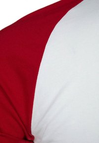 Röd och vit t-shirt med kort ärm och raglan-design; mjukt bomullsmaterial; röda ärmar och vit kropp med en sömlös övergång.