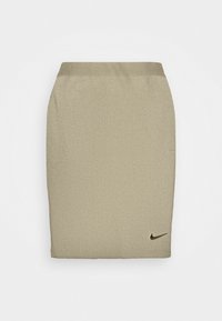 Béžová sukna s žebrovaným vzorem vyrobená z elastického materiálu, s přiléhavým střihem a malým černým logem Nike blízko spodního okraje.