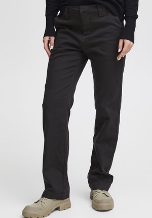 Pantalons noirs à jambe droite en coton avec une texture lisse et des coutures visibles. Comprend des poches avant et une taille avec passants de ceinture.