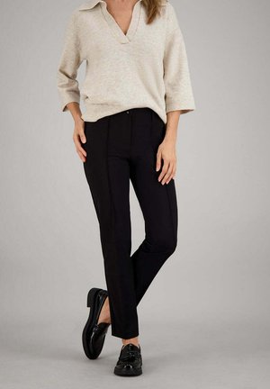 Zwart op maat gemaakte broek met een slanke pasvorm, met een gladde textuur en contrasterende naden, gecombineerd met een lichtbeige gebreide trui.