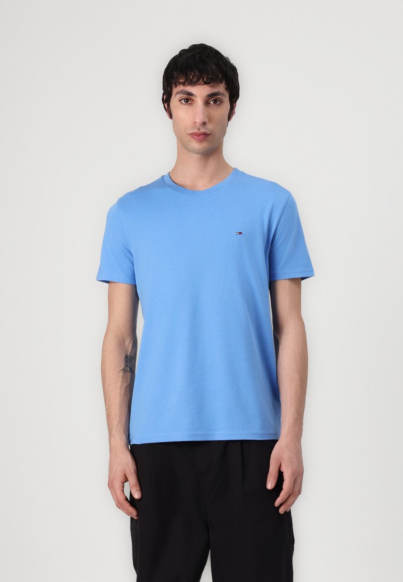 Kurzärmliges T-Shirt mit Rundhalsausschnitt aus leichtem blauen Baumwollstoff, das ein kleines Logo auf der linken Brust und eine glatte Textur aufweist.