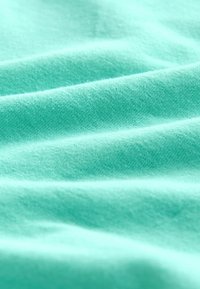 Tela de algodón color turquesa con una textura fina y un brillo sutil, que presenta suaves pliegues ondulantes y un color sólido y uniforme.
