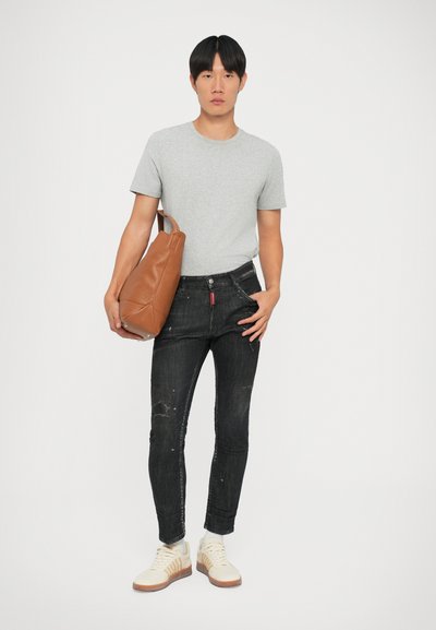 Camiseta gris ajustada, jeans skinny negros desgastados, zapatillas de color claro y un bolso de cuero marrón con una sola correa para el hombro.