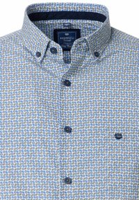 Lichtblauwe overhemden met een geometrisch patroon. Voorzien van een contrasterende donkerblauwe kraag, een klein logo op de borst en donkere knopen.