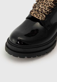 Sorte patent lær ankle boot med en kraftig gummisåle, utstyrt med leopardskrifts snørebånd og en elegant avrundet tådesign.