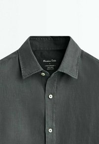 Gray linen shirt with a button-down collar, featuring white buttons, single chest pocket, and a soft, textured fabric. Brand label visible.