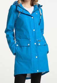 Modrá voděodolná pláštěnka s kapucí, snapovými knoflíky a dvěma předními kapsami. Vyrobena z hladkého materiálu s střední délkou a s možností nastavení.