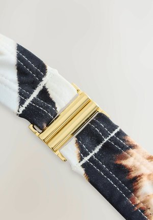 Tekstilbælte i sort og hvidt med en gyldne metallisk spænde i centrum. Stoffet har et falmet mønster og synlige sømme.