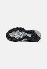 Black and gray sneaker sole featuring a wavy pattern with geometric shapes. Textured surface for grip and stability.
