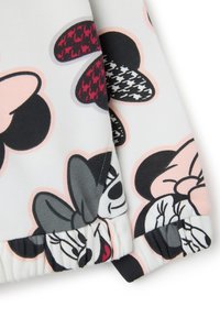 Tissu blanc avec des visages de Minnie Mouse et des nœuds multicolores en rose, rouge, noir et gris, avec des poignets élastiques froncés.