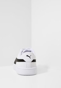 Vita sneakers med svarta accenter, med en texturerad bakpanel, vadderad krage och en liten svart logotyp på hälen. Gummisula.