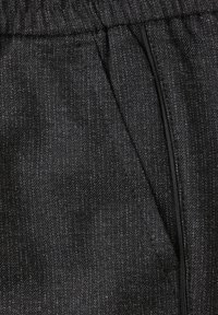 Mustaa teksturoitua kangasta, jossa on herringbone-kuvio. Joustava vyötäyty ja huomaamaton vetoketjullinen tasku sivulla.