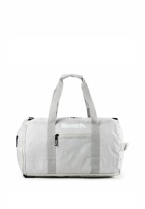 Bolsa de lona gris claro con asas dobles, bolsillo delantero de malla con cremallera, cremalleras laterales y logotipo "Bench." en el centro delantero.