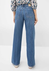 Wide-leg blue jeans made of denim, featuring a high waist, rear pockets, and a label on the back. Smooth texture with folded hems.