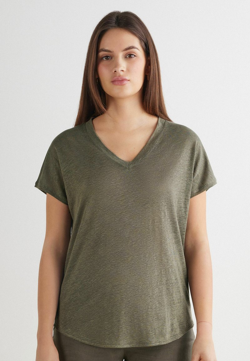 Camiseta de cuello en V de manga corta en verde oliva, textura suave, ajuste relajado, dobladillo ligeramente curvado, diseño simple sin patrones ni herrajes visibles.