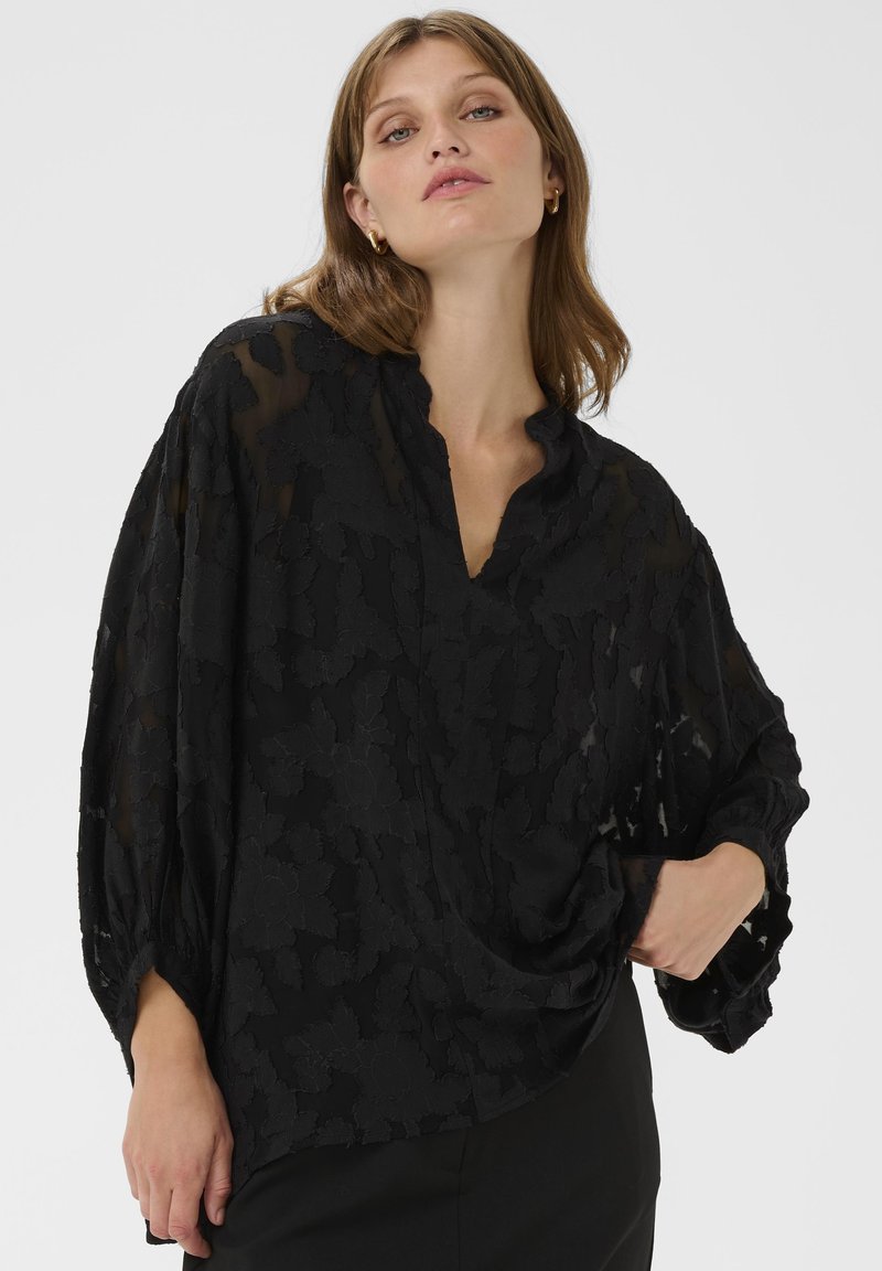 Juoda, raštuota palaidinė su laisvu kirpimu, V formos iškirpte ir pūkuotomis rankovėmis, pagaminta iš lengvos medžiagos. Tekstūruotas gėlių raštas.