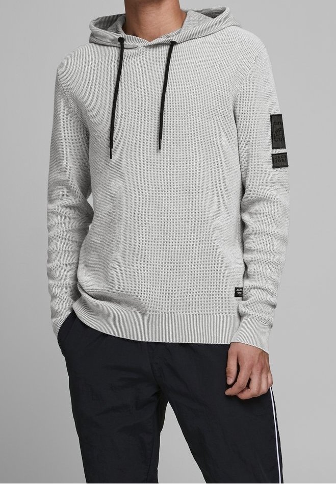 Sudadera con capucha gris texturizada con cordón, dobladillo y puños acanalados. Cuenta con un parche negro en la manga y se lleva con pantalones azul oscuro.