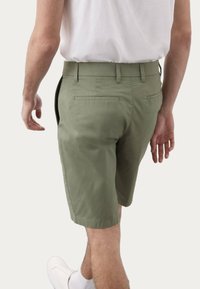 Khaki šortky vyrobené z bavlny, se střihem na míru, bočními kapsami a dvěma zadními kapsami, s čistým lemem a detailem v pase.