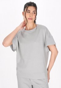 Lys grå kortærmet sweatshirt med et tekstureret geometrisk mønster, rund halsudskæring og løs pasform. Blødt stof og afslappet silhuet.