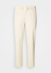 Pantalones de corte relajado en un beige claro, fabricados con un tejido suave, que cuentan con una cintura elástica con cordón y bolsillos laterales.
