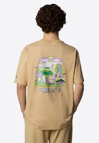 Beige short-sleeve t-shirt featuring a colorful graphic of nature-themed illustrations on the back, with pastel colors and a relaxed fit.