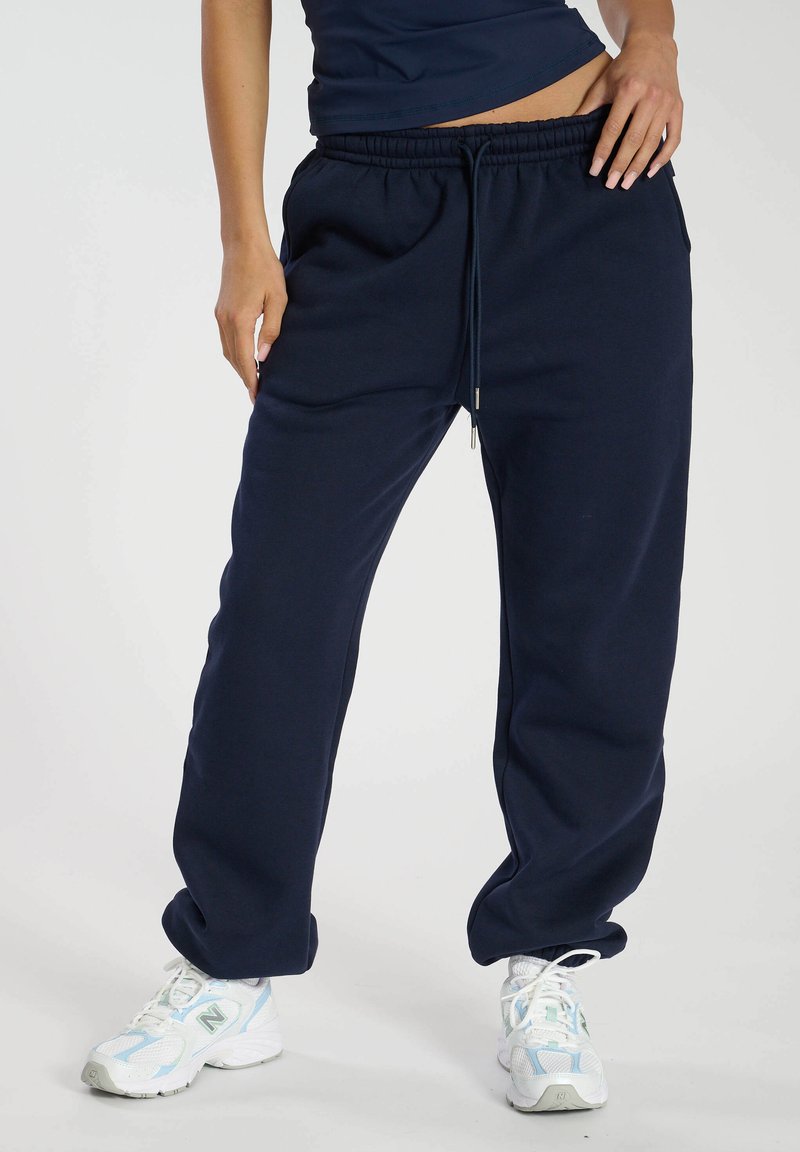Marineblaue Sweatpants mit entspannter Passform, elastischem Bund und verstellbarem Kordelzug. Hergestellt aus weichem Stoff, mit Seitentaschen.
