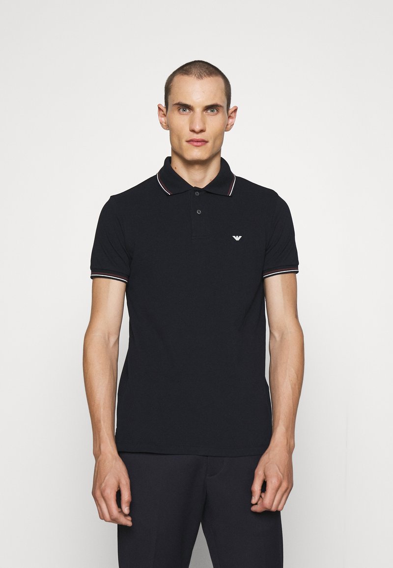 Black polo shirt made of cotton, featuring a three-button placket, short sleeves with striped cuffs, and a small logo on the chest.