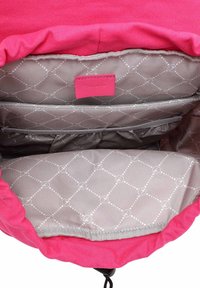 Růžový látkový batoh uvnitř s šedou prošívanou podšívkou, štítek s logem a několik přihrádek pro lepší organizaci. Stahovací šňůrka na vrchu.