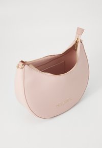 Sac à main en cuir rose pêche avec une forme arrondie, fermeture à glissière et quincaillerie dorée. L'intérieur comprend une petite poche avec un logo.