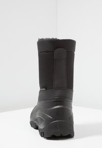 Botte noire imperméable avec une tige synthétique texturée, un talon renforcé et une semelle en caoutchouc dotée d'une bande de roulement à motif pour une meilleure traction.